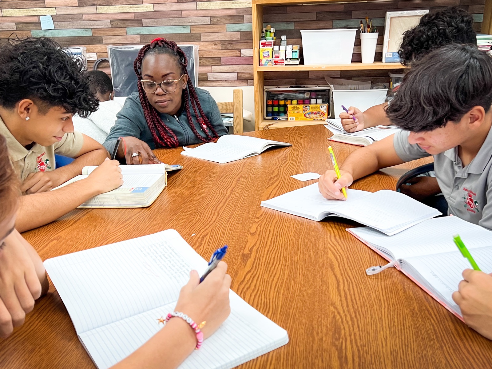 A teacher and students writing together at a table
